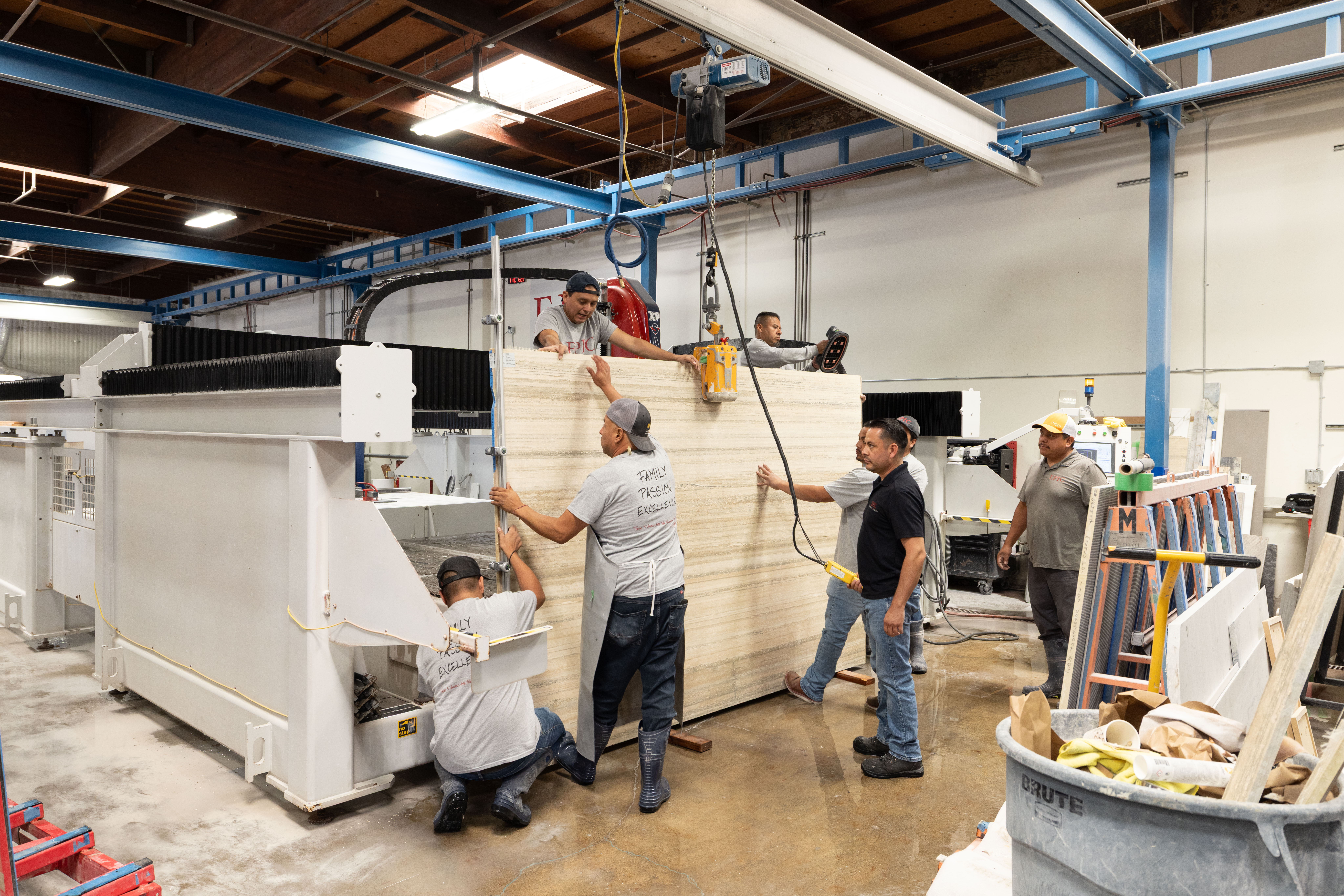 Epic Ceramic & Stone team members fabricating and moving a large natural stone slab in the Orange County fabrication facility.